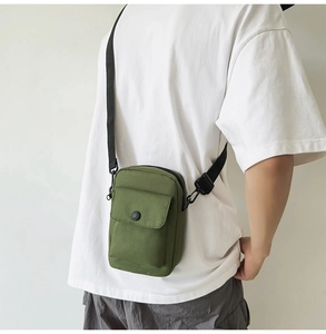 Close-up of a green canvas mini crossbody bag worn by a model to show size and style