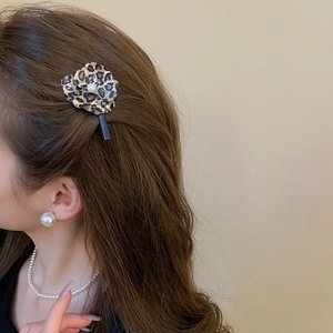 Détail du clip à cheveux fleur léopard avec perle porté par le mannequin