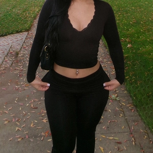 Close-up of black V-neck lace trim detail on long sleeve crop top and slim fit trousers