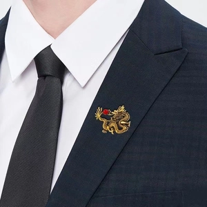 Close-up of golden dragon brooch with red bead on luxury dark blue suit lapel
