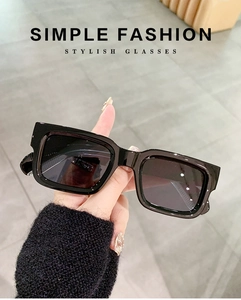 Close-up of black rectangular chunky sunglasses with silver rivets held by hand