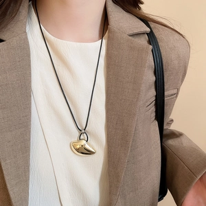 Close-up of irregular gold water drop pendant necklace on model with black rope cord