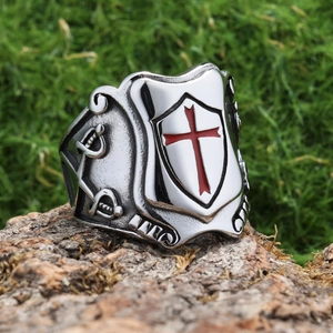 Macro detail of men's vintage shield ring with red cross pattern on a tree bark