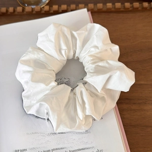 Close-up of white fabric scrunchie with soft pleated texture on an open book