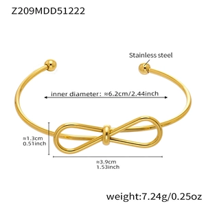 Detailed view of gold stainless steel open bangle with bow design and ball ends