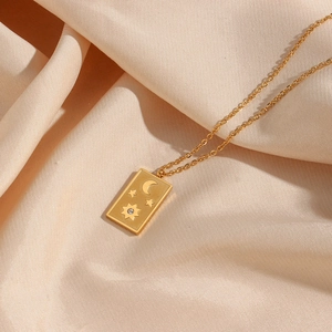 Macro detail of a gold tarot card sun pendant with stars and moon on satin fabric