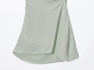 Détail de l'ourlet de robe vert clair montrant la soie et la coupe irrégulière
