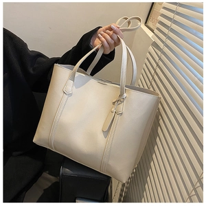 Detail of a large creamy white faux leather tote bag with soft texture and shoulder strap