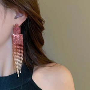 Macro shot of gradient pink rhinestone tassel earrings hanging on model's ear