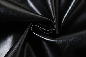 Close-up of black PU leather fabric with fine lychee texture and pleated details