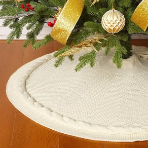 Cream white knitted Christmas tree skirt with cable stitch patterns on wood floor