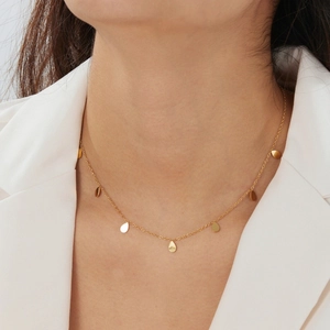 Dettaglio della collana minimalista con pendente a goccia placcata oro su una modella