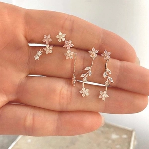 Detail of rose gold flower earrings set with colorful zircons and fringe chain design