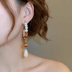 Elegant drop earrings with resin pearls and amber beads on model for luxury jewelry look