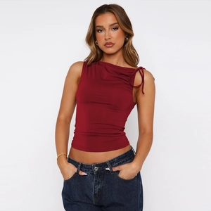 Detail of burgundy ruched crop top showing asymmetric neckline and drawstring texture