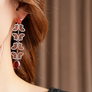 Vue détaillée des boucles d'oreilles papillon en argent avec zircon rouge sur un modèle