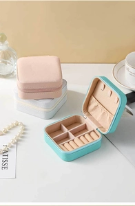 Three elegant leather jewelry boxes in pink, grey, and mint green on a white desk