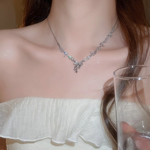 Detailed view of silver bow necklace with sparkling zircon stars on a model's neck