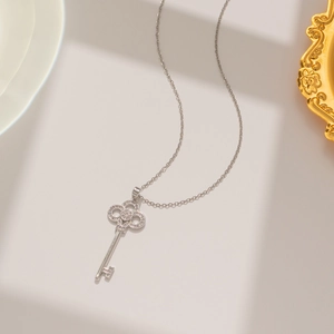 Detailed view of silver titanium steel key pendant with sparkling crystal inlay