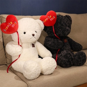 Close-up of black and white teddy bear plush toys holding red hearts with embroidery