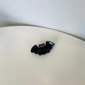Detail of a black sequined bat hair claw clip with white eyes on a white background