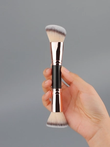Dual-ended makeup brush featuring angled foundation and round powder heads with gold ferrule