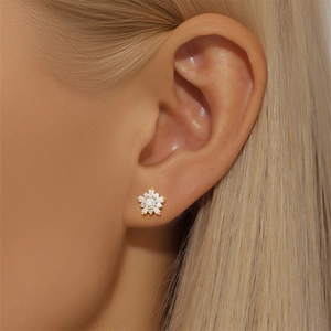 Macro view of gold flower cartilage stud earring with cubic zirconia on model ear