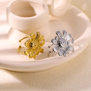 Close-up of gold and silver flower rings on a minimalist ceramic holder