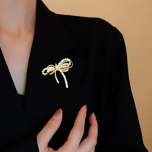Eleganter Gold-Schleifen-Brosche mit Zirkonia und Perlen an einem schwarzen Revers