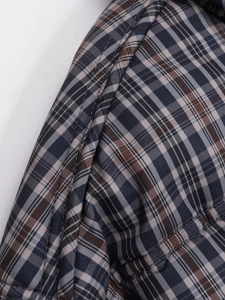 Macro detail of navy blue and brown plaid pattern with quilted stitching on a padded jacket