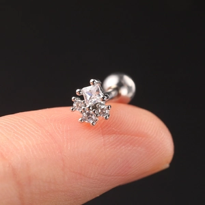Macro shot of silver zircon helix stud on fingertip showing its miniature geometric size