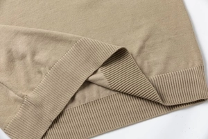 Close-up detail of khaki slim-fit knitted sweater showing ribbed hem and texture