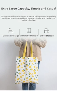 Detail of canvas tote bag with lemon print and yellow handles held by a model