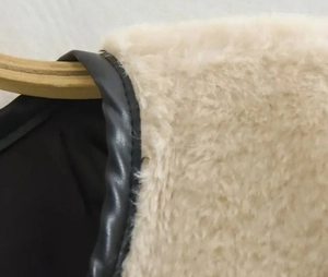 Gros plan sur les coutures en fausse fourrure beige et les garnitures en cuir noir