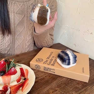 Detail of plush AirPods case with burger-style design, metal zipper and pearl pendant charm
