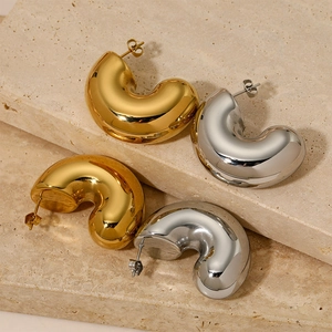 Minimalist hollow C-shaped hoop earrings in gold and silver finish on stone background