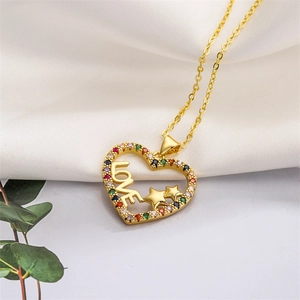 Close-up of golden heart pendant with colorful crystals and LOVE engraving on white silk