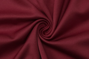 Dettaglio del tessuto in maglia rosso vino con eleganti pieghe radiali e trama