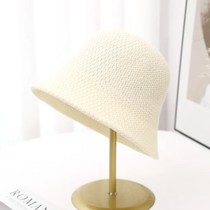 Close-up of cream knitted bucket hat showing breathable crochet texture on a gold stand