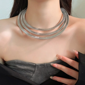 Close-up of triple-layered silver spring snake chain necklace worn by a model