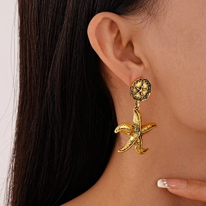 Detailed view of vintage gold starfish earrings with textured finish worn by a model