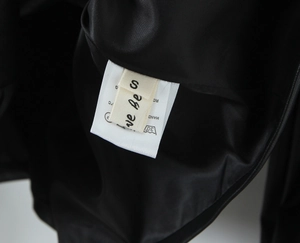 Détail de l'étiquette de taille S et des conseils d'entretien sur une veste en cuir noir