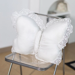 Macro detail of white butterfly plush pillow featuring delicate lace embroidery edges