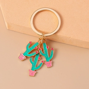 Detail of a golden metal keychain with three green enamel cactus charms in pink pots