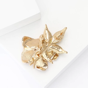 Detail view of the gold-tone metal back and secure pin clasp of the narcissus brooch