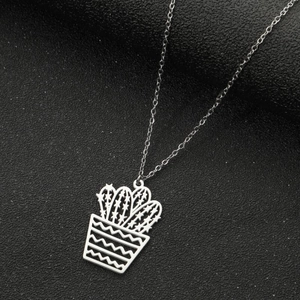 Macro shot of silver stainless steel cactus pendant necklace on a dark textured surface