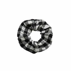 Elastic black and white checkered fabric scrunchie with pleated texture on white background
