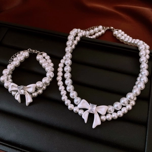 Close-up of double-layer pearl necklace and bracelet set with bow on black tray