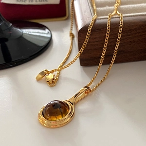 Elegant gold necklace featuring an oval amber pendant on a delicate vintage metal chain