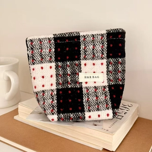 Detail of checkered canvas makeup bag with red polka dots and branded cloth label